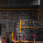 brick wall with red hydrants and yellow piping in an urban alleyway setting
