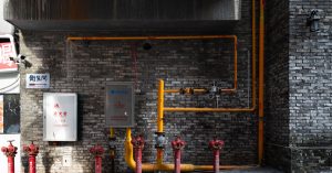 brick wall with red hydrants and yellow piping in an urban alleyway setting