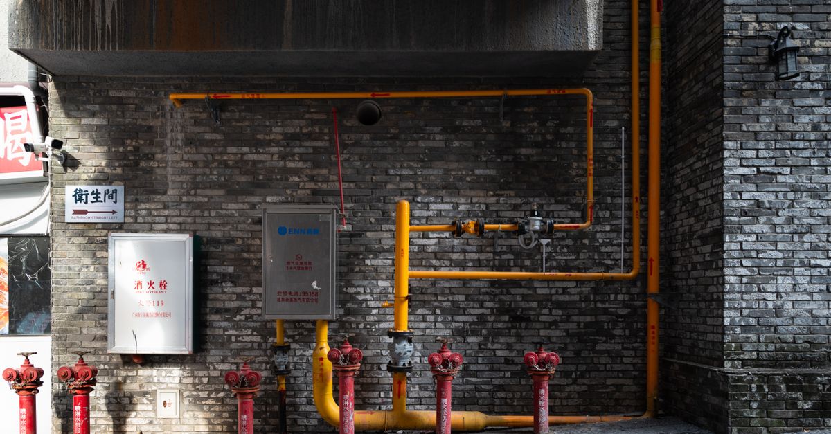 brick wall with red hydrants and yellow piping in an urban alleyway setting